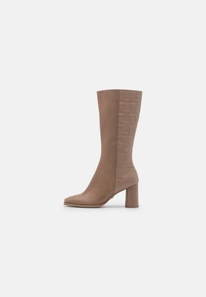 Botte en cuir taupe mi-mollet avec talon bloc et motif géométrique embossé sur le côté extérieur, vue de côté extérieur, sur fond blanc.