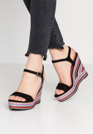Sorte ruskind wedgesandaler med en multicolor fletrem-design, der har en spænde-ankelrem og en mønstret sål.