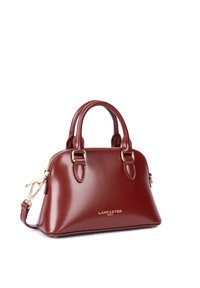 Sac à main en cuir bordeaux avec quincaillerie dorée, deux poignées supérieures et une bandoulière amovible. Possède une finition lisse et brillante ainsi qu'un détail de logo.