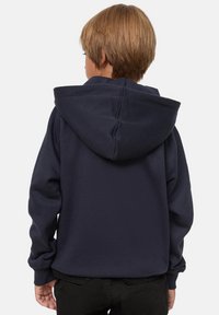 Felpa navy realizzata in un tessuto morbido, con un grande cappuccio, polsini a costine e una vestibilità rilassata. Sul retro presenta dettagli di cucitura.