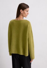 Groene gebreide trui met een losse pasvorm, brede mouwen en ribbelstructuur. Ontworpen met een wijde halslijn en een iets kortere rug.