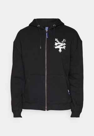 Black zip-up hoodie made of cotton blend. Features a front pocket, silver zipper, and a white graphic design on the left chest.