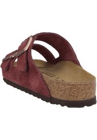 Sandal in suede bordeaux con due cinturini regolabili, suola in sughero e suola in gomma texturizzata. Caratterizzato da un accento a fiocco vicino ai cinturini.