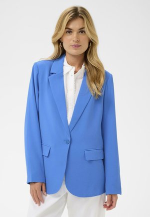 Modro blazer z oblikovano prileganjem, zapenjanjem na en gumb, dvema žepoma spredaj in gladko teksturo, nošen preko bele bluze.