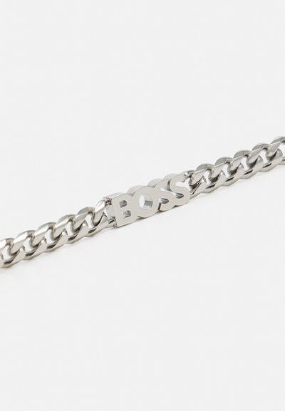 Bracelet en chaîne en argent avec un design à maillons épais et un logo "BOSS" central. Texture lisse avec finition polie.