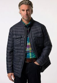 Marineblaue Steppjacke mit Stehkragen und Fronttaschen, ausgestattet mit horizontalen Nähten und einer glatten, leicht glänzenden Textur.