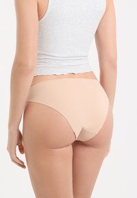 Sous-vêtements nude sans coutures avec une coupe taille haute, fabriqués en tissu lisse, dotés d'une ceinture douce et de coutures minimales pour un confort optimal.