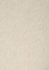 Beige breiwerk met een zachte textuur en fijn stikpatroon, met een uniforme uitstraling en minimale variatie in toon.