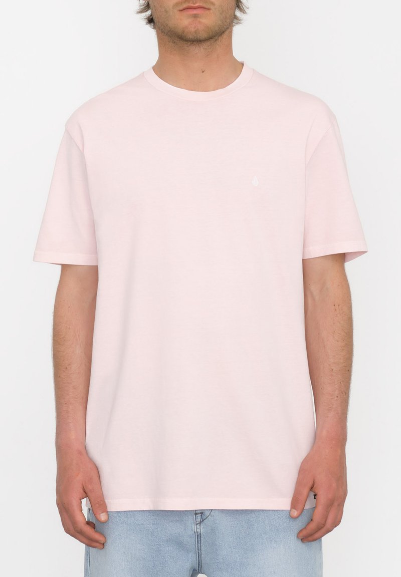 Camiseta de manga corta color rosa claro hecha de algodón suave. Presenta un cuello redondo y un pequeño logo de la marca en el pecho. Diseño sencillo.