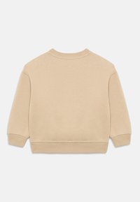 Felpa beige con scollatura rotonda, spalle scese e polsini a costine. Tessuto morbido e testurizzato con un design semplice e senza decorazioni visibili.