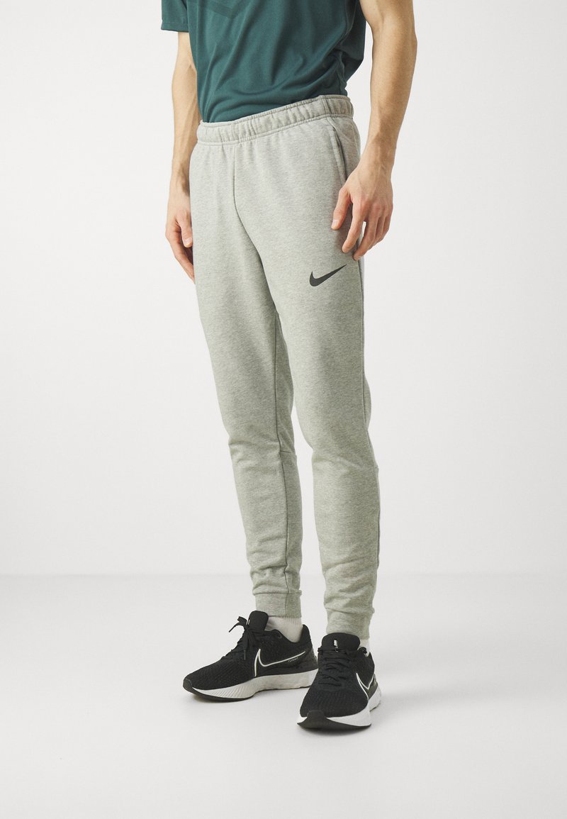 Sive bombažne hlače s elastiko v pasu in stranskimi žepi. Na levem stegnu ima črni Nike logo. V kombinaciji z črnimi športnimi copati.