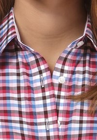 Kraget ternet skjorte i pink, blå og brun plaidmønster; har hvide knapper og en glat stofoverflade.