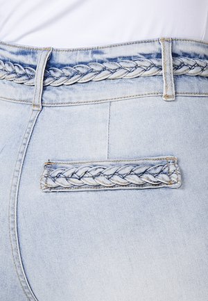 Jean en denim bleu clair avec un détail de ceinture tressée et une poche tressée décorative. Texture lisse avec des coutures renforcées.