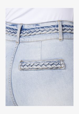 Világoskék farmernadrág, fonott derékpánt részlettel és díszítő fonott zsebbel. Simább textúra, megerősített varrással.