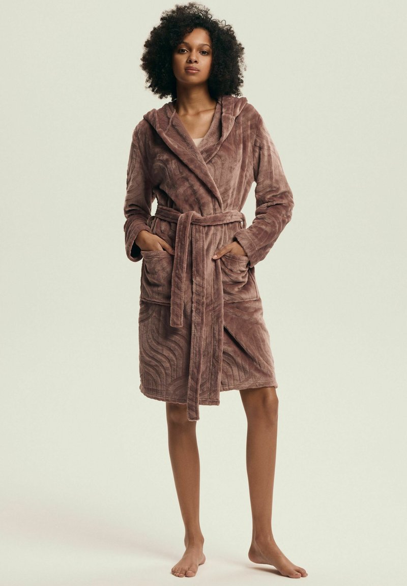 Pluszowy fioletowy szlafrok o teksturowanym, falistym wzorze, z długimi rękawami, kapturem i wiązanym paskiem. Posiada dwie przednie kieszenie.