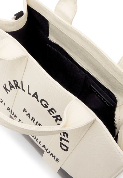 Бяла платнена чанта с черен интериор, с надпис "Karl Lagerfeld Paris" и джоб с цип отвътре.