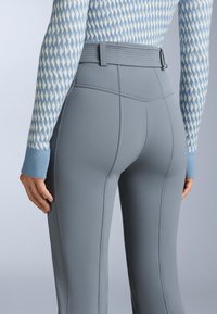 Grå högmidjade leggings med ribbad midja, med slät yta och sömdetaljer, kombinerade med en mönstrad blå tröja.