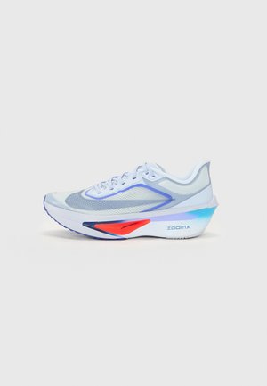 Chaussure de course blanche et grise avec des accents bleus et rouges, empeigne en mesh respirant, semelle épaisse et rembourrée étiquetée "ZoomX", présentée sur un fond uni.