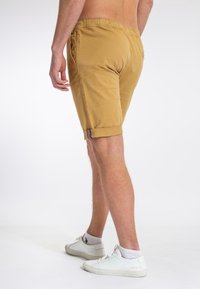 Khaki szorty z elastycznym pasem i podwiniętymi mankietami, z subtelnym paskiem w stylu prążków po boku. Wykonane z lekkiego materiału.