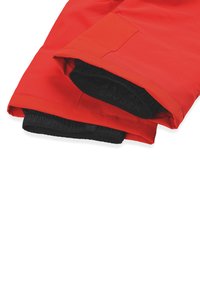 Giacca impermeabile rossa con polsini elastici, una tasca con velcro e una fodera interna nera. Il materiale è liscio e resistente.