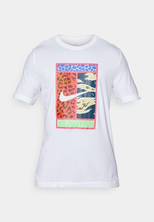 T-shirt bianco in cotone con una stampa grafica colorata caratterizzata da motivi animalisti, forme astratte e un logo Nike centrale. Collo rotondo e maniche corte.