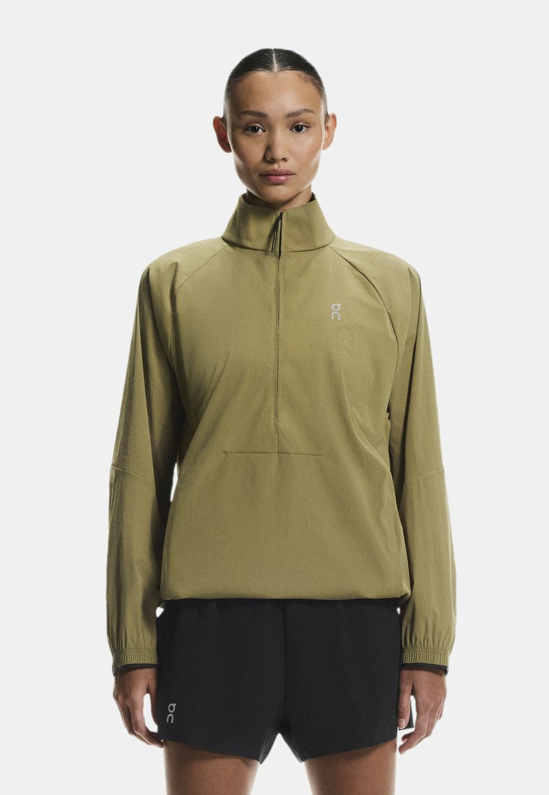 Olíva zöld, negyedzipzáras dzseki hosszú ujjakkal, raglán kialakítással és diszkrét logóval a mellrészen. Fekete sorttal párosítva. Sima tapintású.