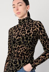 Turtleneck top met luipaardprint in doorschijnende, lichte stof met zwarte, groene en beige patronen. Lange mouwen en een aansluitend ontwerp accentueren de vorm.