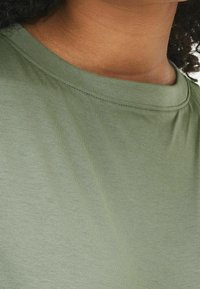 Oliwkowy t-shirt z okrągłym dekoltem, wykonany z miękkiego, lekkiego materiału o subtelnej teksturze. Czysty, prosty design.