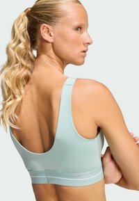 Light blue sports bra made from stretch fabric, featuring a scoop back, thick straps, and a contrasting white band at the bottom.