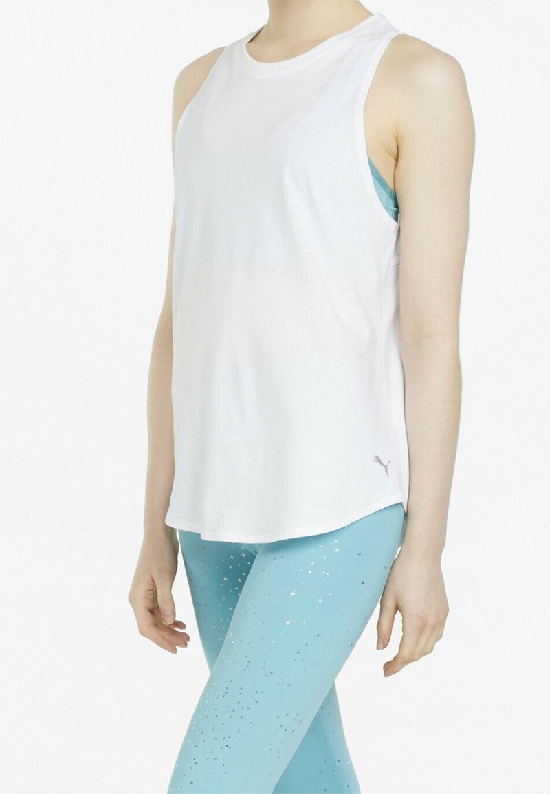 Top sin mangas blanco con cuello redondo; presenta un sutil logo de la marca. Combinado con leggins azul claro decorados con patrones de estrellas plateadas.