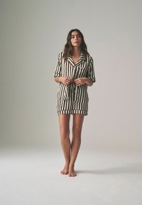 Zwart-wit gestreepte korte pyjama set met een kraag, korte mouwen, een zak en een tailleband. Zachte stof met een gladde textuur.