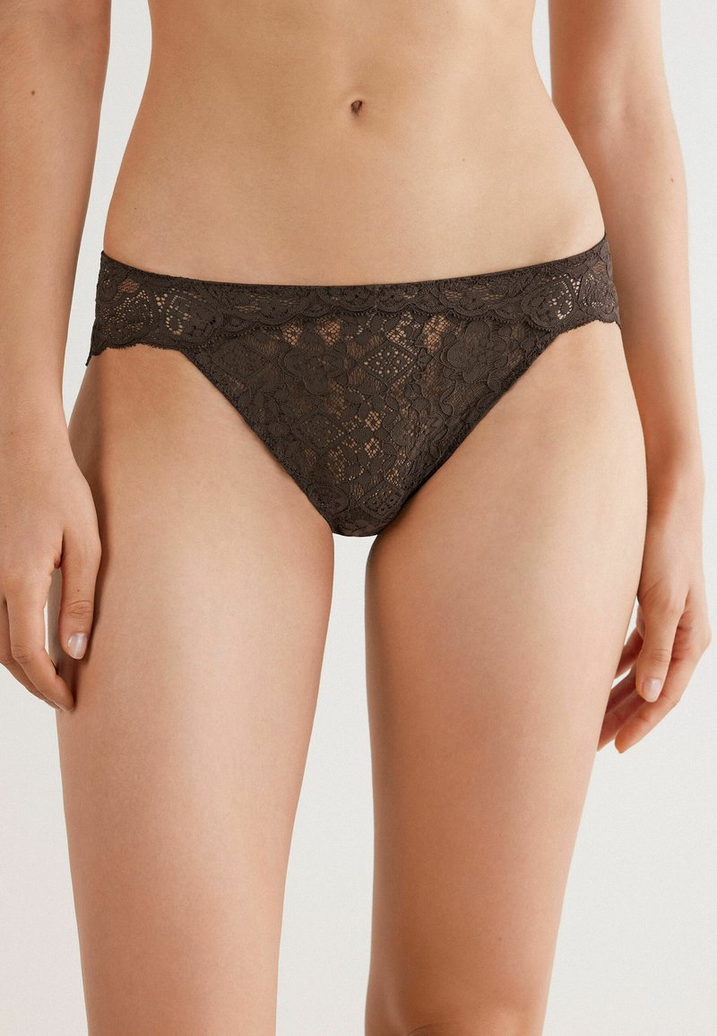 Braunes Spitzenbikini mit floralem und diamantförmigem Muster, ausgestattet mit einem gewellten Bund, transparenter Textur und minimaler Bedeckung.