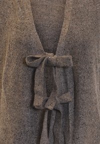 Brun stickad kofta med V-ringning och knytband framtill. Tyget har en strukturerad, fläckig yta.