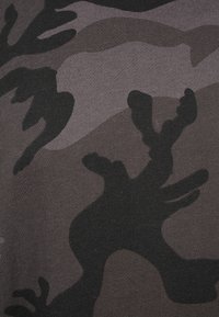 Tela con patrón de camuflaje en tonos de negro y gris, que presenta formas abstractas y una textura suave. Diseñada para un uso versátil.