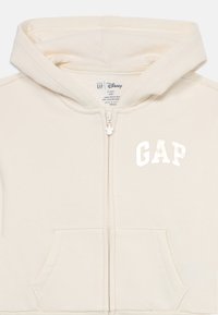 krémová detská mikina s kapucňou, predným zipsom, klokanie vrecko, logo "GAP" na hrudi a zips s príveskom Mickey Mouse, veľkosť 4 roky.