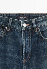 Denim blue jeans by Massimo Dutti with a button closure, contrasting stitching, and a faded texture. Tag visible inside waistband.