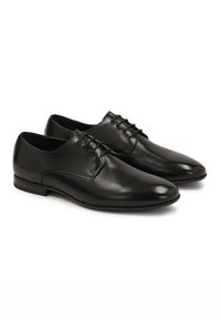 Scarpe eleganti in pelle nera con finitura liscia, punta a forma affusolata, design con lacci e dettagli di cucitura sottili sui lati.