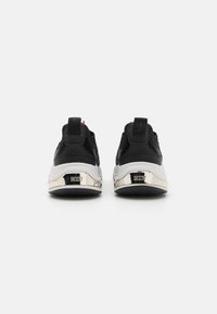 Melni sports apavi ar zamšiem un acs audumu, baltu gumijas zoli un metāliskām zelta akcentiem pie papēža. Iezīmē DKNY zīmolu un rozā detaļu.