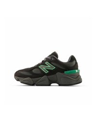 Sneaker nera con dettagli verdi, realizzata in materiali mesh e scamosciato, design chunky e suola testurizzata per una migliore aderenza.
