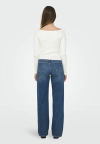 Weißes, geripptes Langarmoberteil mit weitem Ausschnitt, kombiniert mit hoch taillierten blauen Jeans aus Denim mit geradem Bein und zwei Gesäßtaschen.