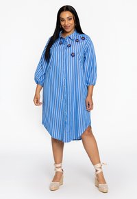Blauwe gestreepte jurk met knoopsluiting aan de voorkant, oversized mouwen en decoratieve bloemenaccenten op de borst. Textuurstof.