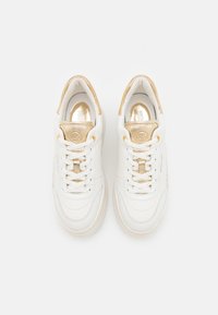 Baskets en cuir blanc avec accents dorés, lacets et logo Michael Kors sur la languette, vues de dessus sur un fond blanc.
