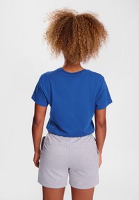 Blauw katoenen T-shirt met korte mouwen, gecombineerd met lichtgrijze katoenen shorts. De set heeft een ontspannen pasvorm en een eenvoudig ontwerp.