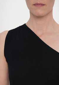 Čierny rebrovaný top s asymetrickým výstrihom, ktorý má jednoramenný dizajn a textúrovanú látku. Strih je priliehavý a elegantný.