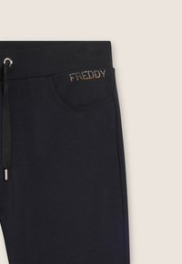 Pantaloni jogger neri con tasca laterale decorata con un cristallo che forma la parola "FREDDY" e una vita con coulisse. Tessuto morbido e liscio.