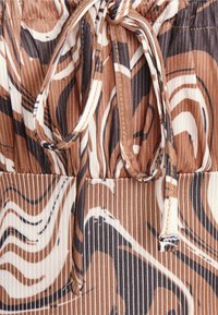 Tecido estampado em marrom e branco com designs em onda, apresentando uma cintura com cordão e material texturizado e pregueado.