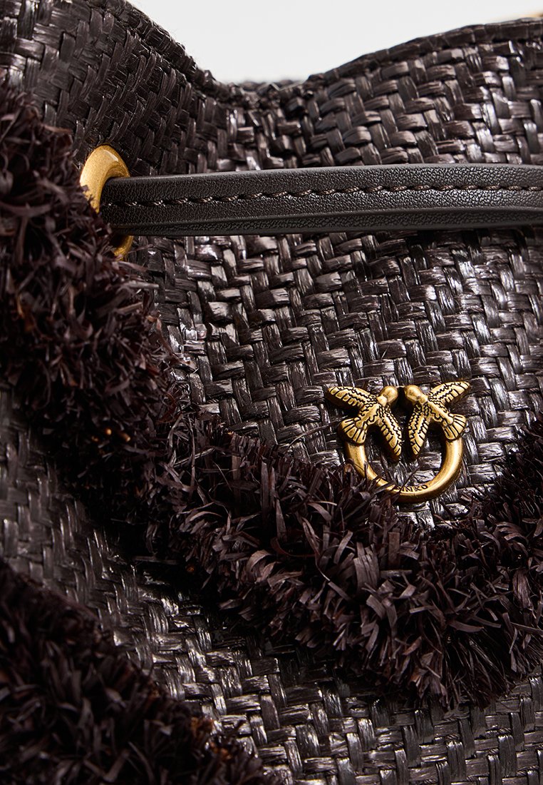 Czarna pleciona torebka o teksturowym wykończeniu, z pozłacaną ozdobą w kształcie pszczoły oraz ciemną skórzaną rączką z kontrastowym ściegem.