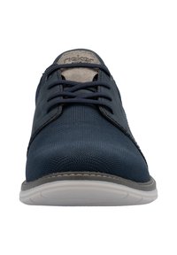 Chaussures lacées bleu marine avec une tige en tissu texturé et des accents en daim. Elles présentent une semelle en caoutchouc blanche et des coutures renforcées sur les bords.