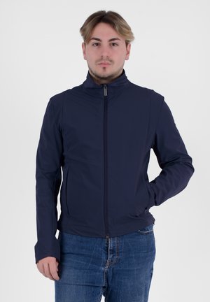 Giacca blu navy con colletto alto, zip frontale e texture liscia. Presenta tasche laterali, design aderente e stile minimalista.