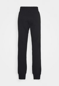 Černé tepláky vyrobené z měkké bavlny, s tapered střihem a elastickým pasem a žebrovanými manžetami. Žádné vzory ani akcenty nejsou viditelné.